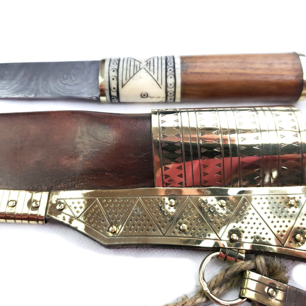 Close up decorations Rus Viking Damascus Knife #56D is a replica Viking Knife with decorated veg tanned with brass decorations Sheath and features Norse decorative motifs carved in the bone handle accented with brass, and a Damascus blade that is sturdy