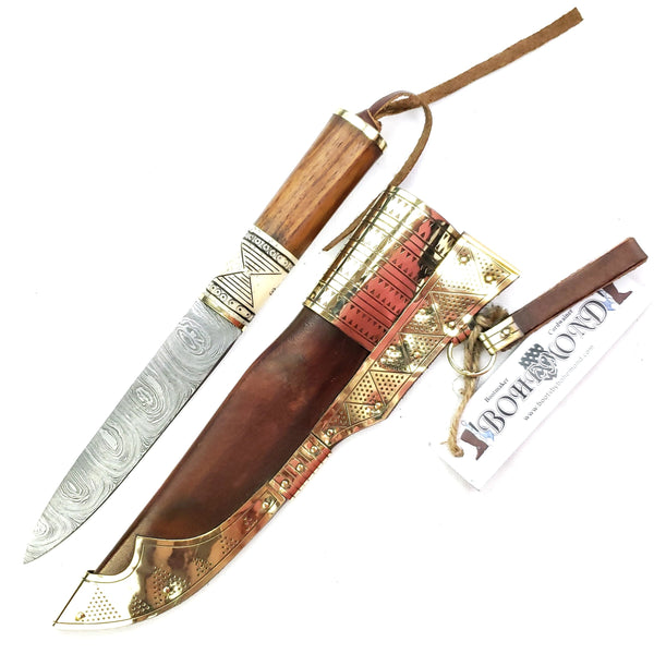 Knife next to sheath Rus Viking Damascus Knife #56D is a replica Viking Knife with decorated veg tanned with brass decorations Sheath and features Norse decorative motifs carved in the bone handle accented with brass, and a Damascus blade that is sturdy